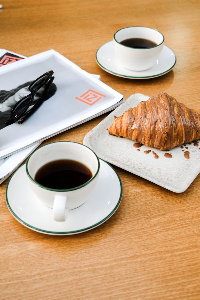 Cozy café scene with coffee, croissant, and newspaper in Adana's warm ambiance.